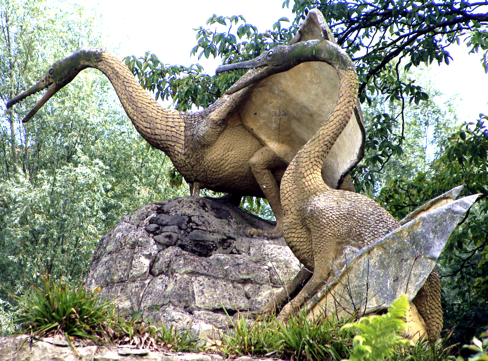 A photograph of the two surviving Crystal Palace "pterodactyles". They look like reptilian geese, with small heads, long toothy jaws, long swan-like necks, folded membranous wings, and skin covered in large overlapping snake-like scales.